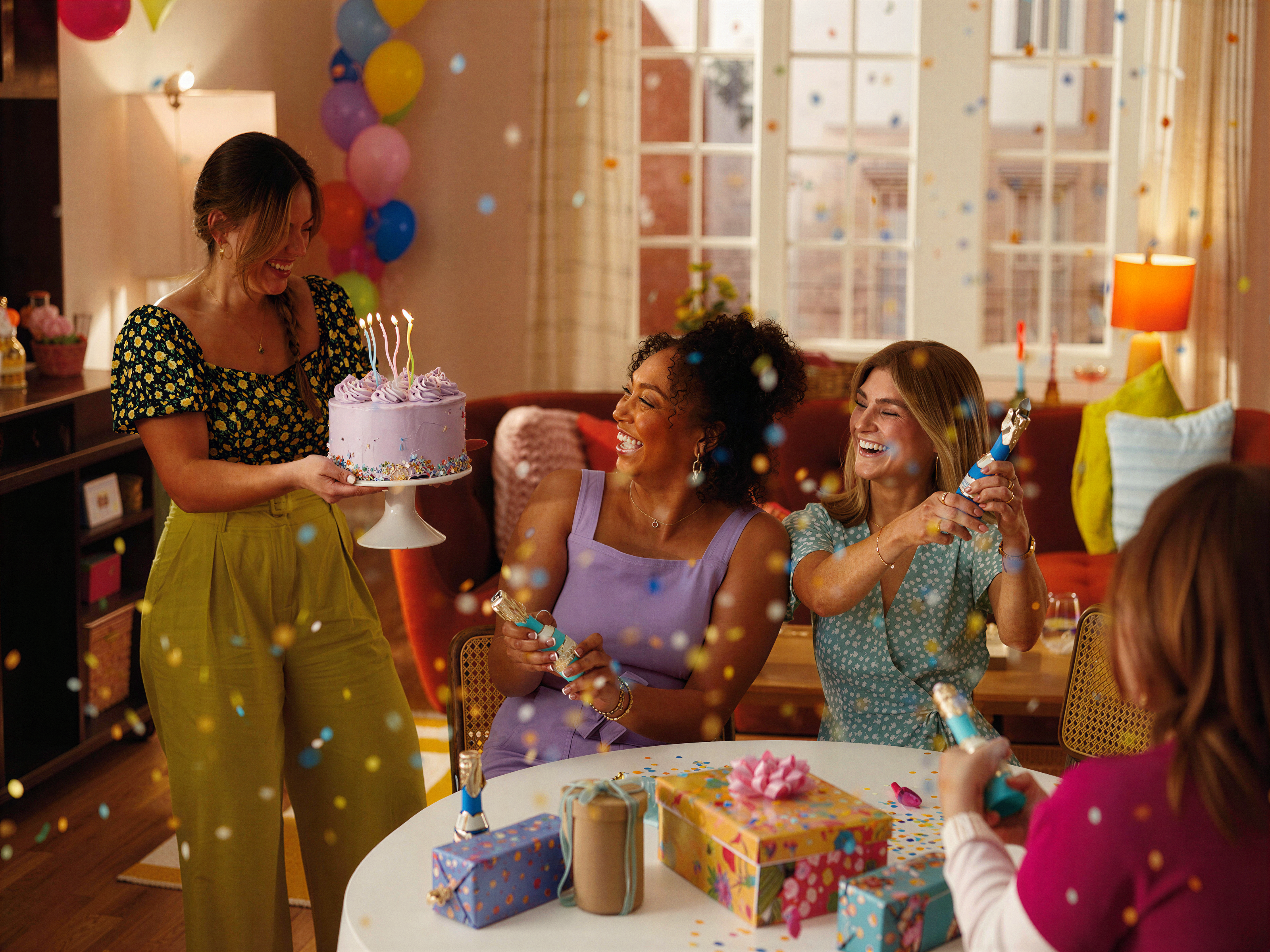 Friends celebrating a birthday with cake and confetti