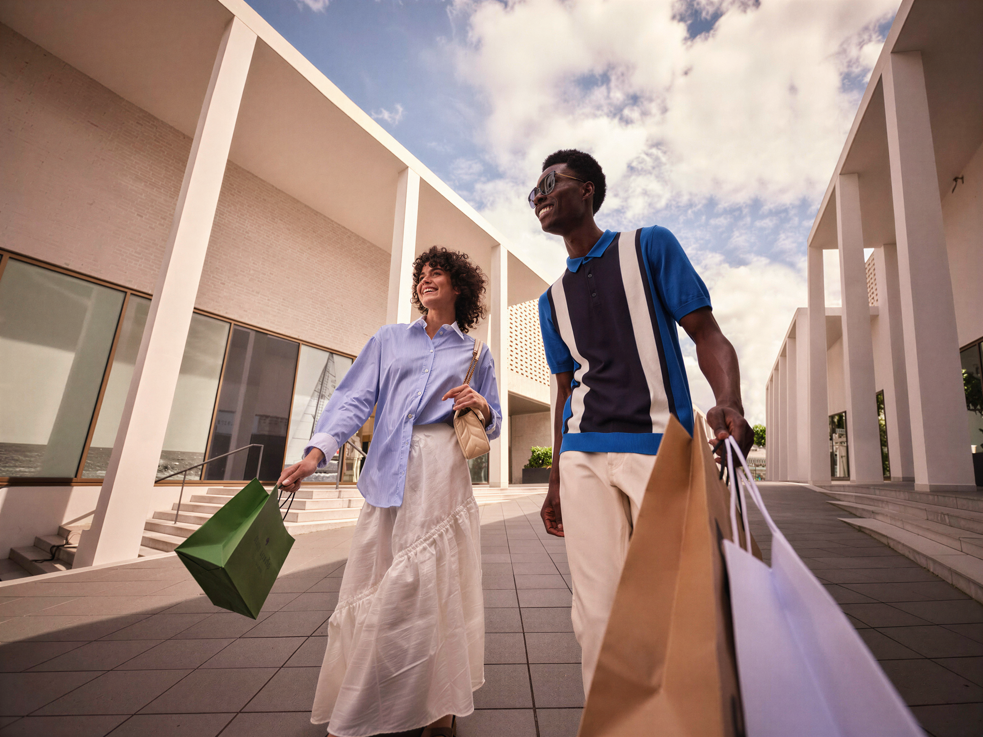 A man and a woman walking with shopping bags on a sunny day